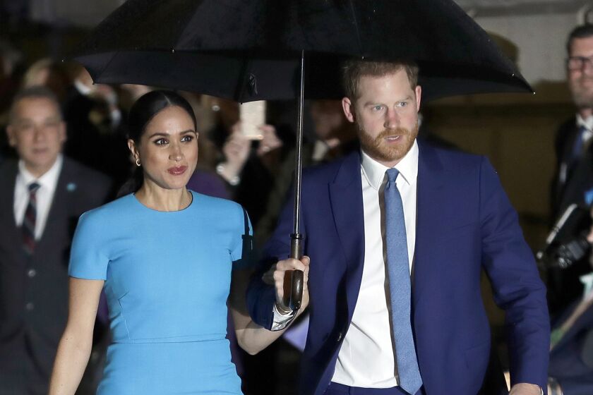 Meghan and Prince Harry walking with an umbrella