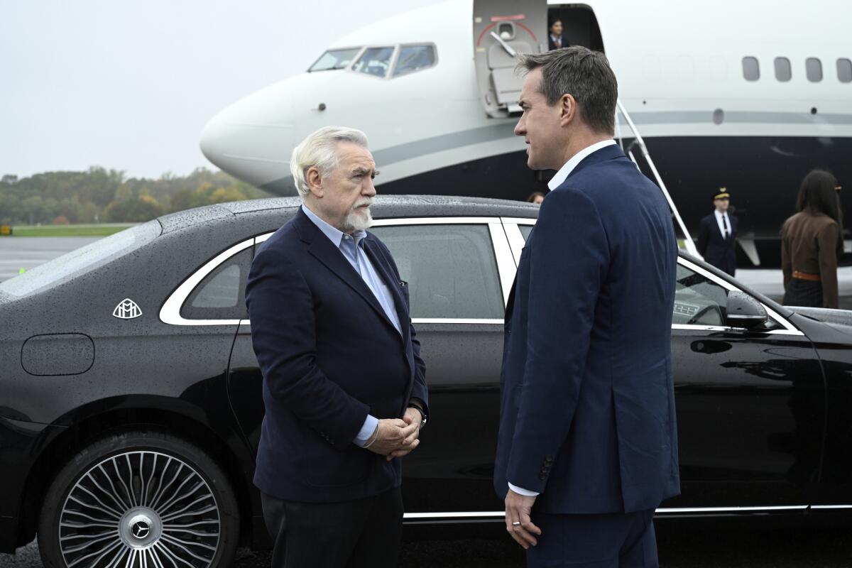 Two men wait beside a car to board a private jet