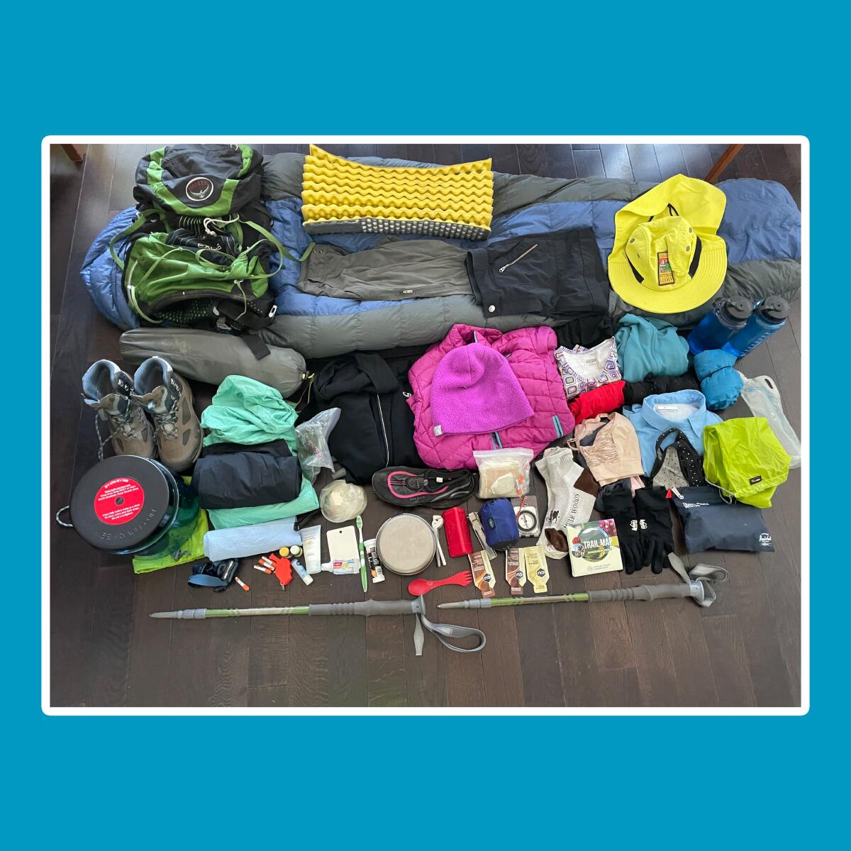 Hiking equipment piled neatly on a hardwood floor.