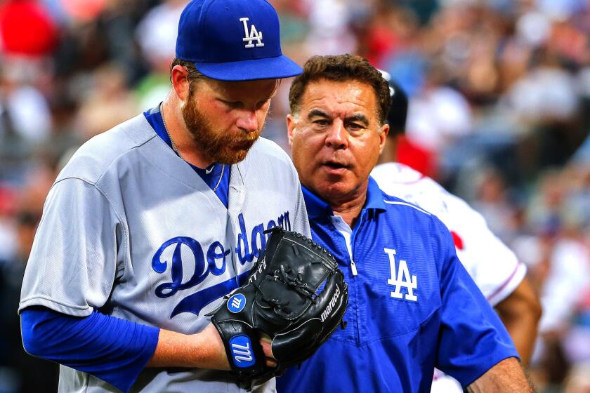Dodgers starting pitcher Brett Anderson exits the game with trainer Stan Conte after injuring his left Achilles' tendon during the game against the Braves onJuly 21 in Atlanta.