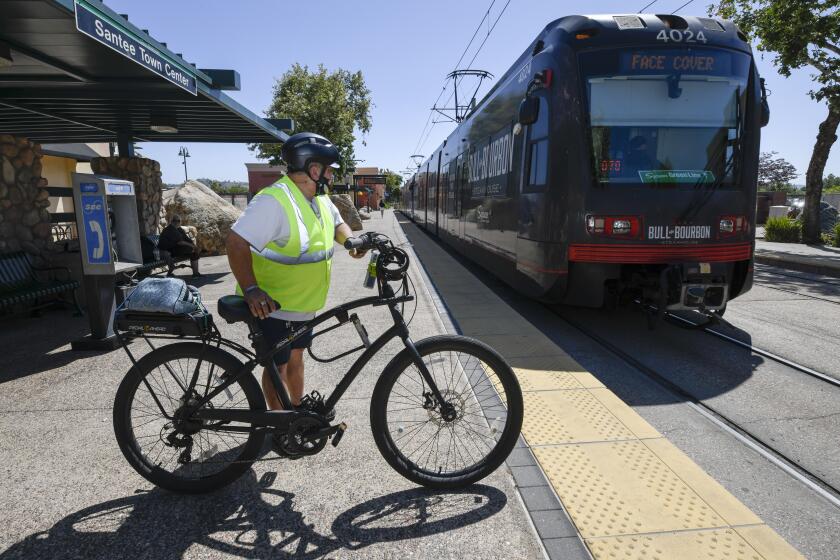 Roddy Jerome waits for the trolley with his bike at the Santee Town Center Wednesday, May 26, 2021 in Santee, Calif. Jerome commutes from his job in Santee to his home in City Heights. (Photo by Denis Poroy)