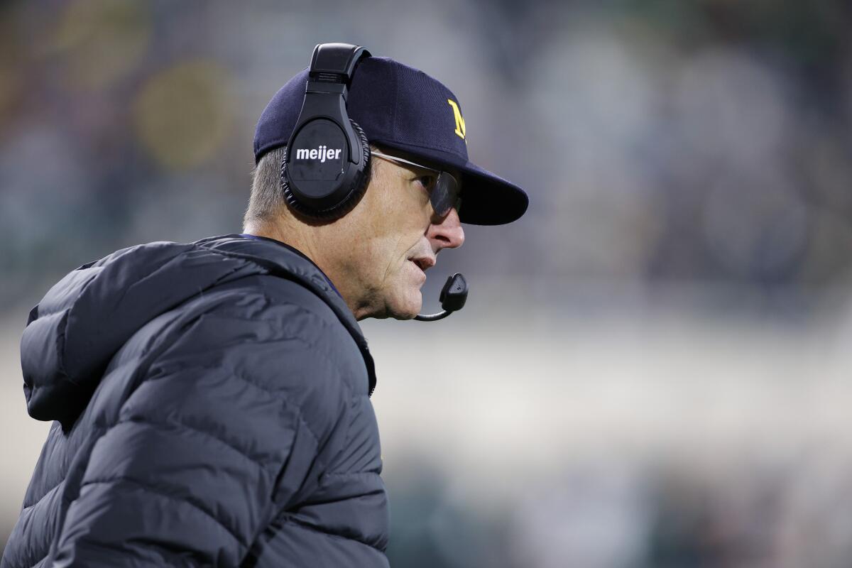 Michigan coach Jim Harbaugh wears a headset along the sideline while watching the Wolverines play.