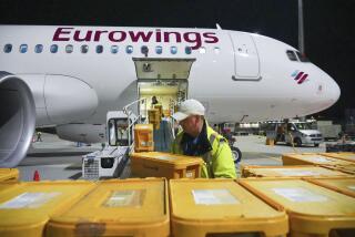 Empleados de WISAG cargan un Airbus A320-214 de Eurowings que se dirige a Stuttgart con cajas de plástico cargadas de cartas y paquetes, en el aeropuerto Berlin Brandenburg, en Schönefeld, Alemania, el 28 de marzo de 2024. (Soeren Stache/dpa vía AP)