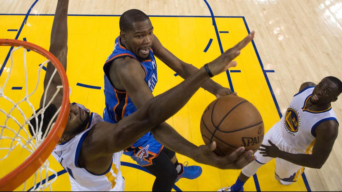 Thunder forward Kevin Durant tries to score on a drive to the basket against Warriors center Festus Ezeli, left, and forward Draymon Green during Game 2 on Wednesday night.