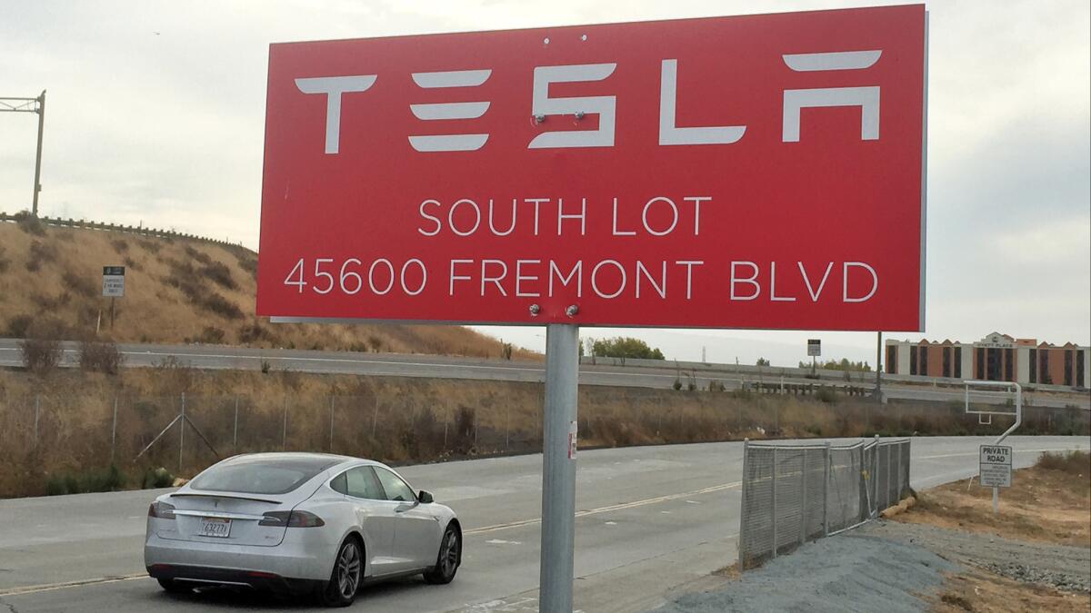 A car approaches Tesla's assembly plant in Fremont, Calif. The electric car company's proposed merger with solar energy equipment provider SolarCity is being challenged in court.