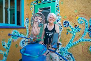 MAR VISTA, CA - Aug. 13, 2024: Lori Powers stands by a sculpture in the backyard of her Mar Vista home. (Michael Owen Baker / For The Times)