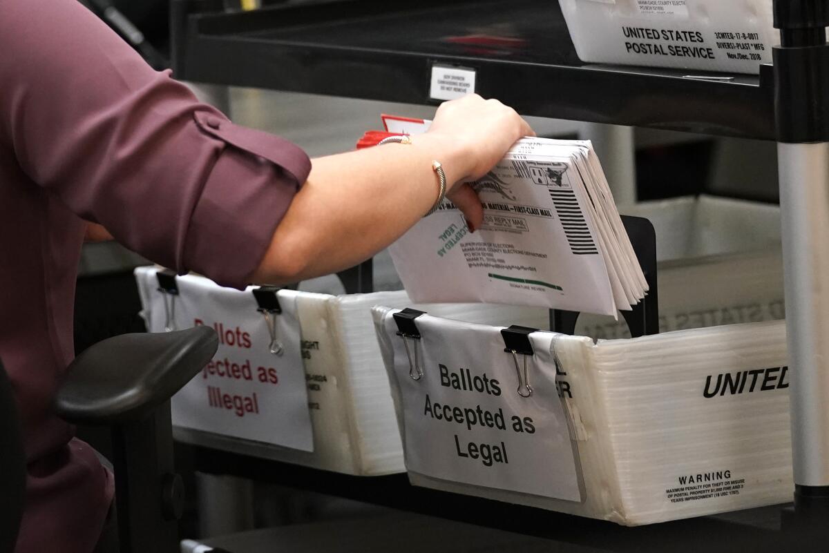 An election worker sorts vote-by-mail ballots at the Miami-Dade County Board of Elections in Doral, Fla., in 2020.