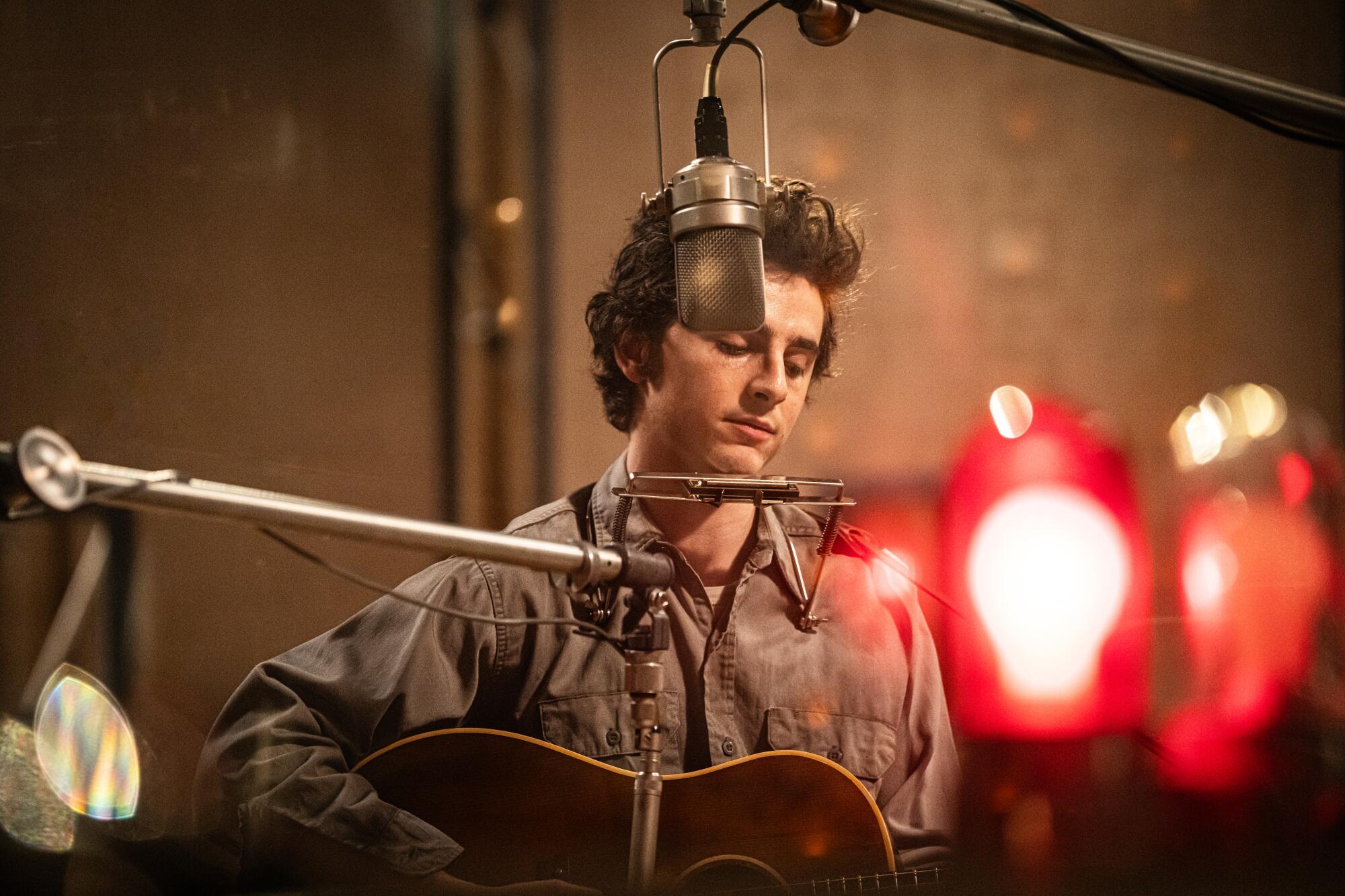 A people creator plays guitar successful a signaling studio.