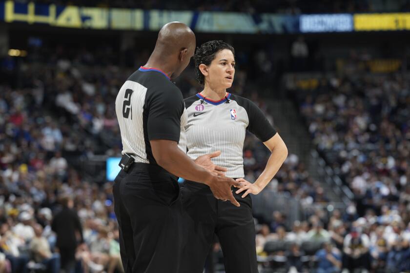 Referee Dedric Taylor (21) chats with referee Cheryl Flores (91) in the first half of an NBA basketball game Sunday, April 9, 2023, in Denver. (AP Photo/David Zalubowski)