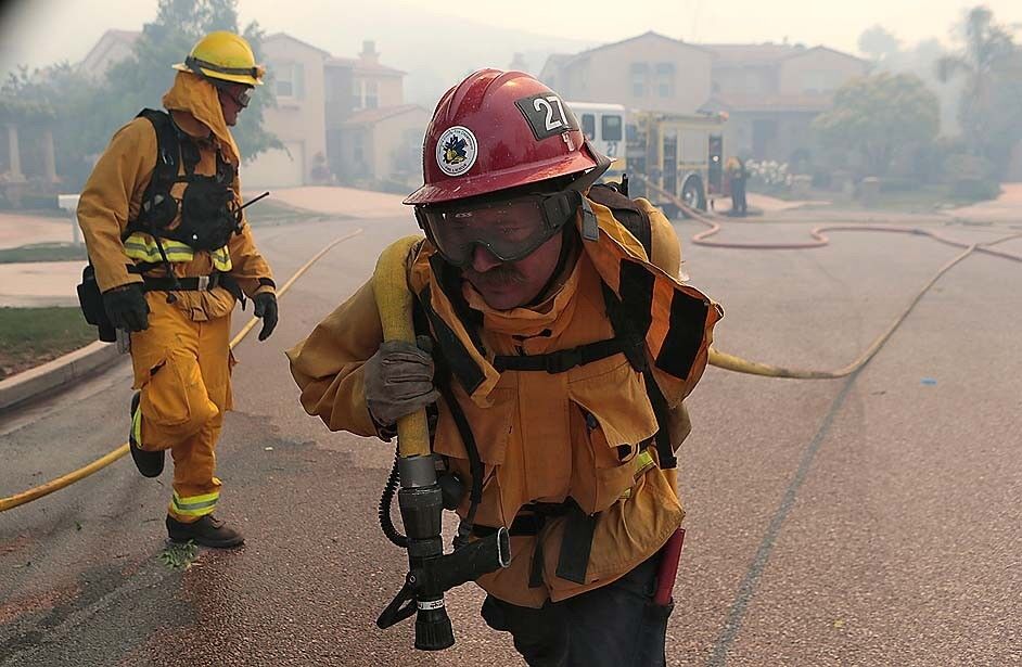 Ventura County firefighters prepare hoses on Via Santa Ana as they fight the Springs fire in Newbury Park.