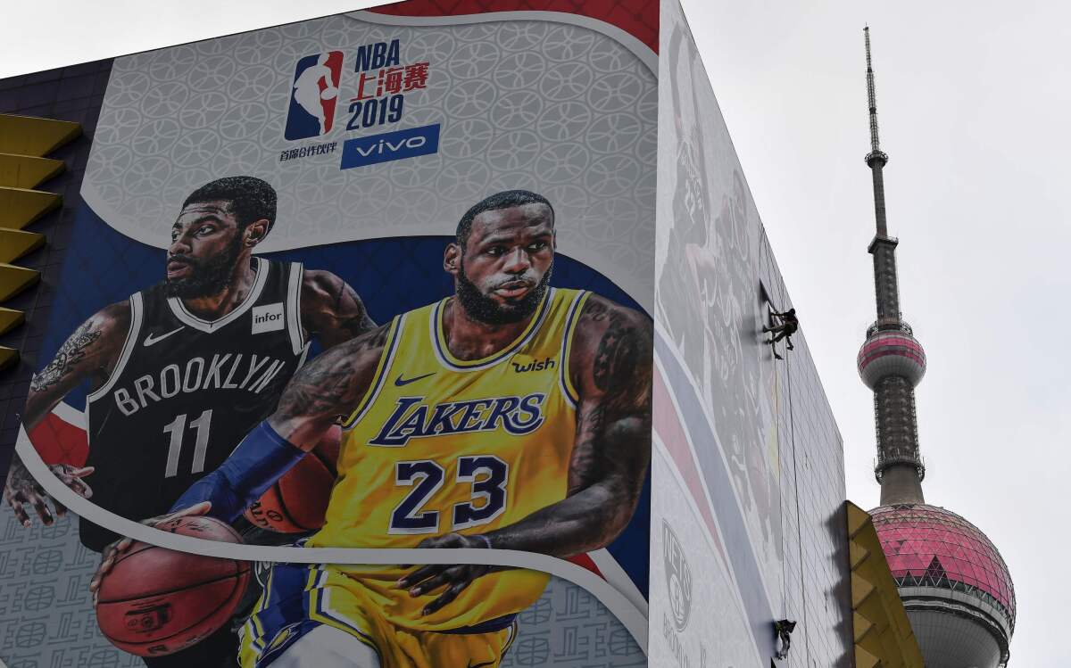 A worker removes a promotional banner from a building in Shanghai on Wednesday promoting a scheduled exhibition game between the Lakers and Brooklyn Nets.