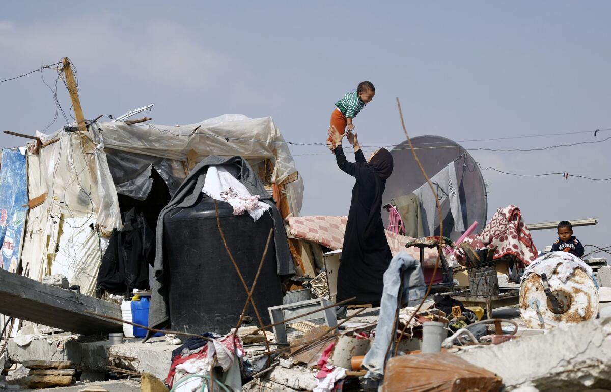 A Palestinian woman plays with her child on the rubble of their family's home, which was destroyed during the 50-day war between Israel and Hamas in the Gaza Strip.