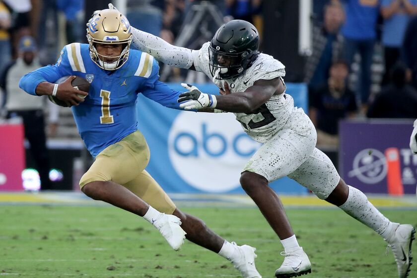 PASADENA, CALIF. - OCT. 23, 2021. UCLA quarterback Dorian Thompson-Robinson is brought down for a loss by Oregon saftety Vernon McKInley III in the fourth quarter at the Rose Bowl in Pasadena on Saturday, Oct. 23, 2021. . (Luis Sinco / Los Angeles Times)