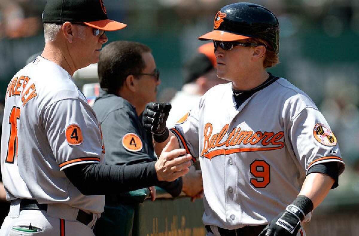 Orioles outfielder Nate McLouth is congratulated by hitting coach Jim Presley scoring a run against the Athletics during a game last week in Oakland.