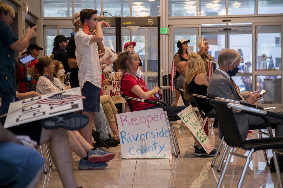 Residents who want public health orders rescinded crowd together in the lobby to watch video monitors of an emergency Riverside County Board of Supervisors meeting Friday at the County Administrative Center.