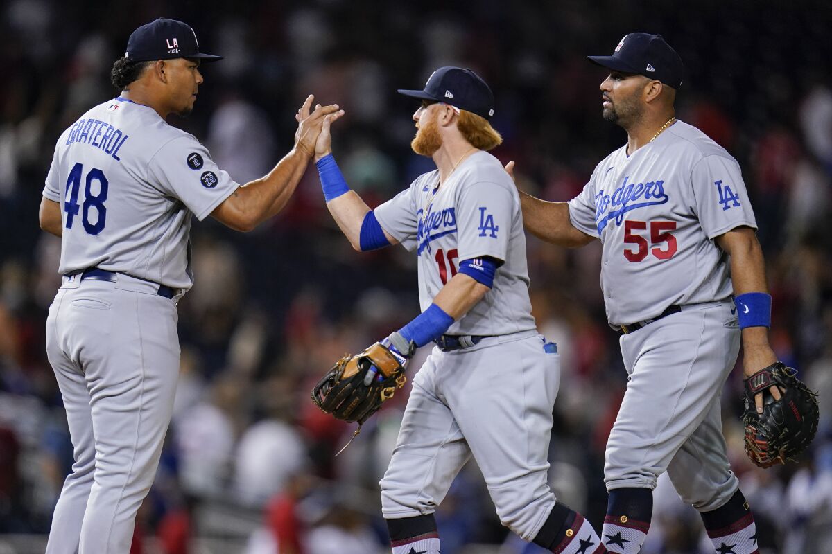 Los Angeles Dodgers relief pitcher Brusdar Graterol, left, third baseman Justin Turner, center, and first baseman Albert Pujols celebrate after recording the last out of a baseball game against the Washington Nationals, Friday, July 2, 2021, in Washington. The Dodgers won 10-5. (AP Photo/Julio Cortez)
