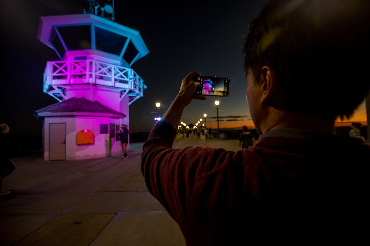 Andy Hsieh, from New Zealand, takes a photograph of Huntington Beach Lifeguard Tower Zero Tuesday.