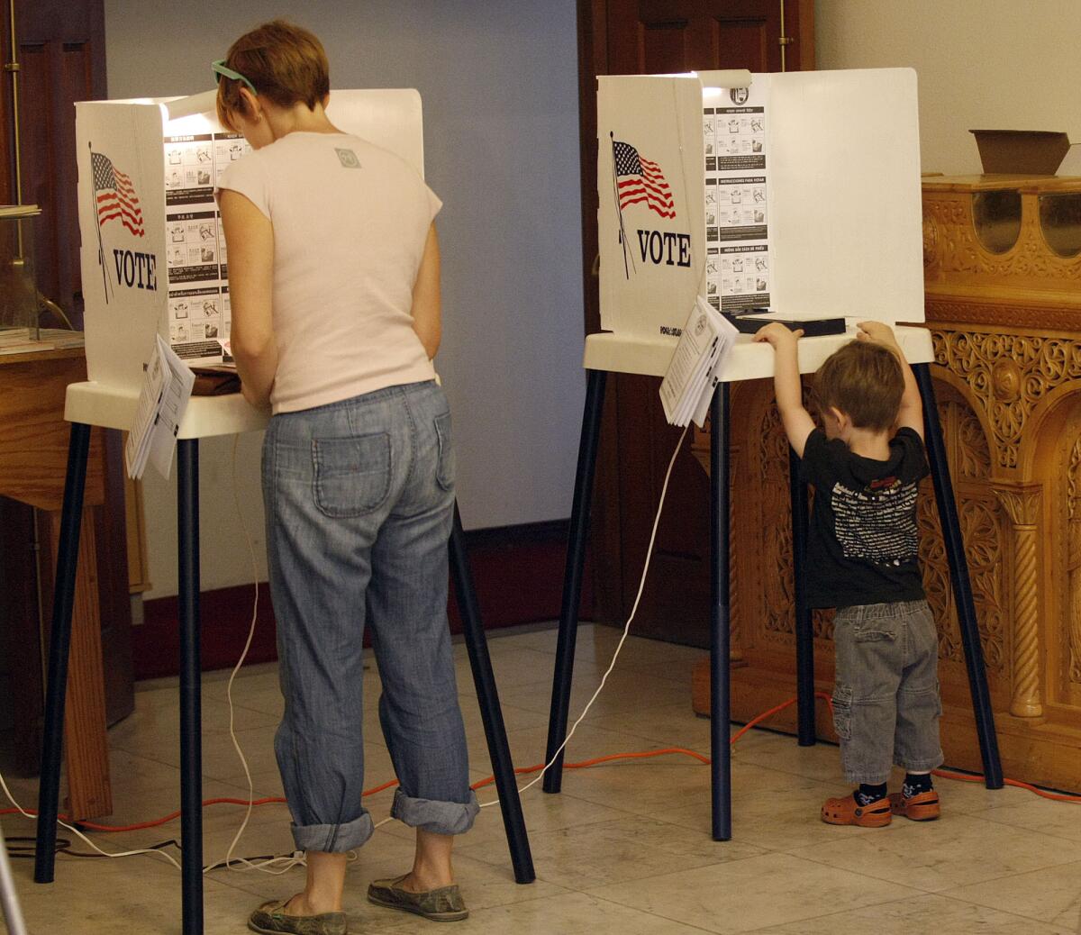 A Los Angeles mother votes in the June primary as her son checks out the equipment.