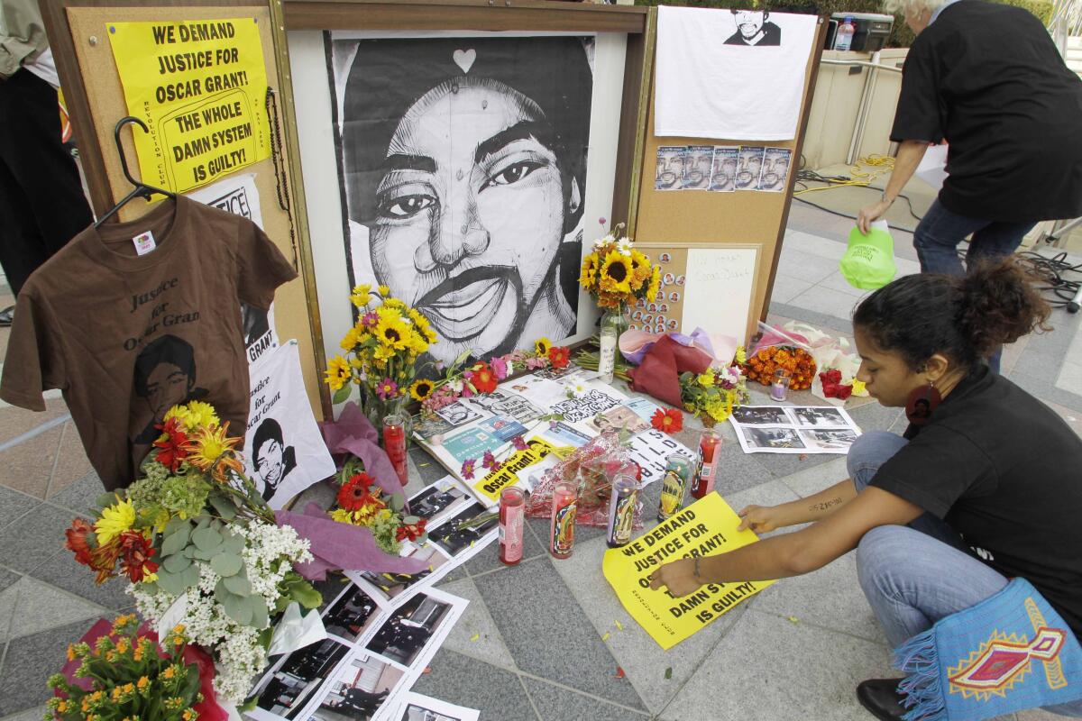 A woman leaves a sign at a memorial for Oscar Grant. 