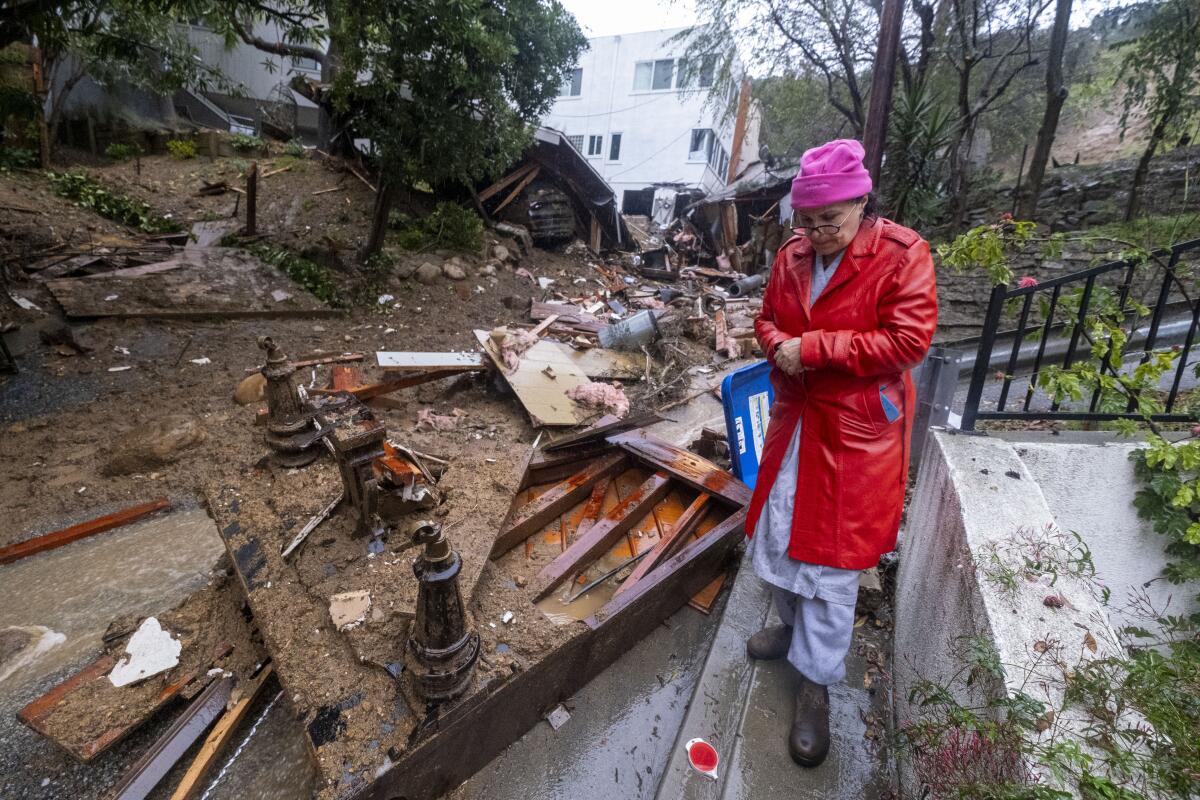 A person walks past a grand piano flipped on its top and other debris lying in the street