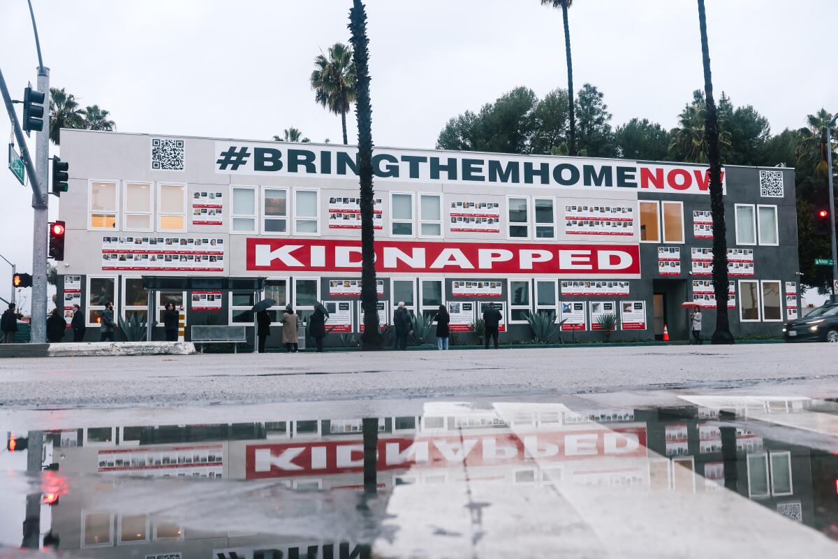 An art installation on the side of a long multistory building includes the words "bring them home now" and "kidnapped."
