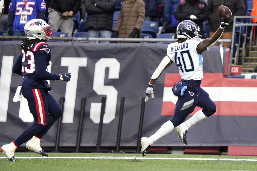 Tennessee Titans running back Dontrell Hilliard, right, raises the football after beating New England Patriots safety Kyle Dugger (23) on his 68-yard touchdown run during the first half of an NFL football game, Sunday, Nov. 28, 2021, in Foxborough, Mass. (AP Photo/Mary Schwalm)