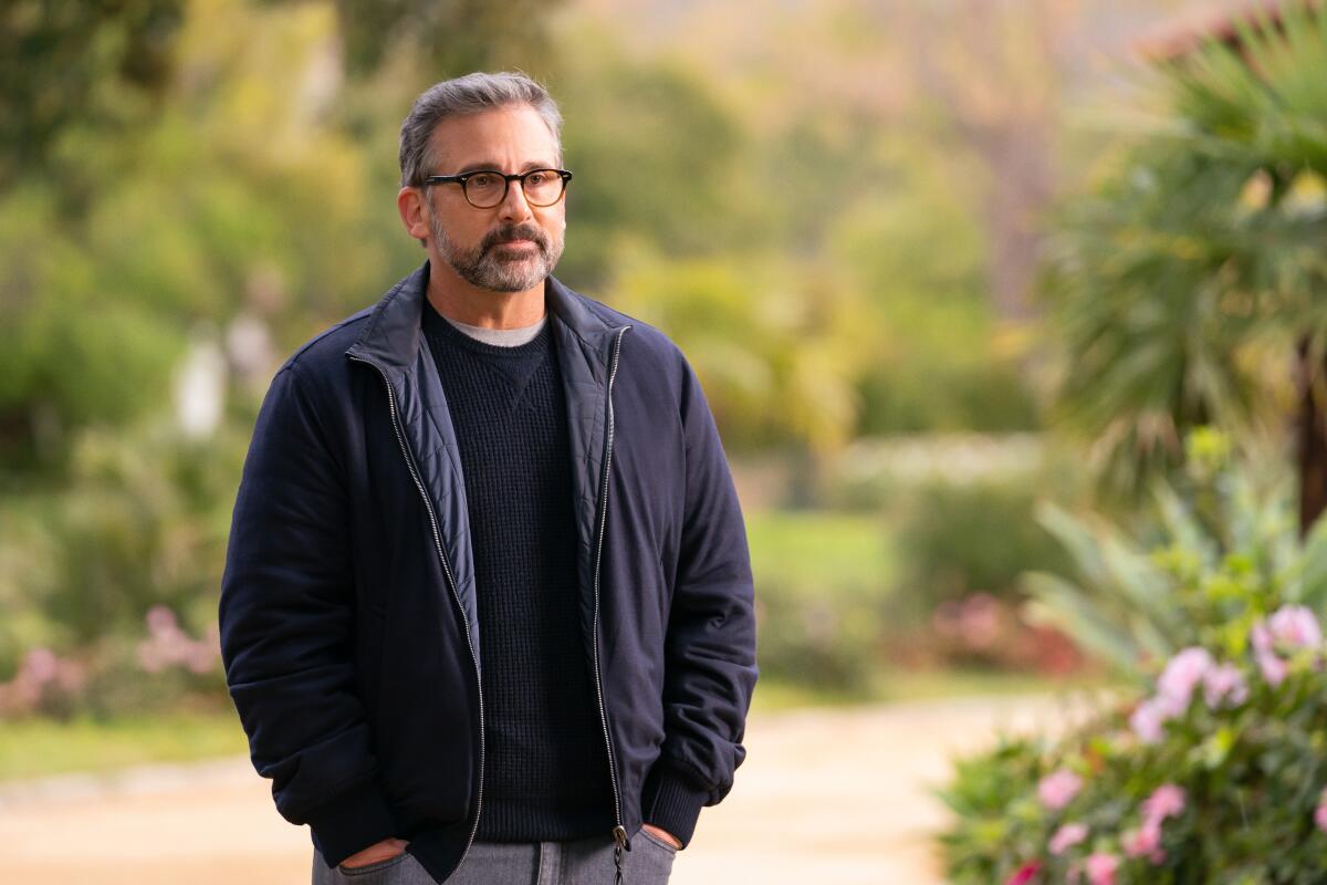 A man with gray hair and beard in a dark jacket and glasses