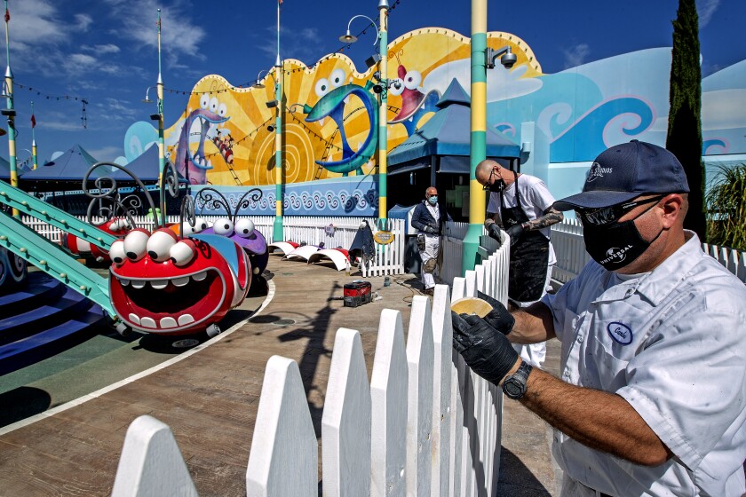 Six Flags Magic Mountain reopens: COVID safety measures
change even the bathrooms 2 UNIVERSAL CITY, CA - MARCH 17, 2021: Left to right-Scenic artists Billy Teichert, Jason Young, and Carlos Rivas prepare to paint a fence located next to a silly swirly ride at Super Silly Fun Land on the grounds of Universal Studios Hollywood that will re-open in the near future. (Mel Melcon / Los Angeles Times)