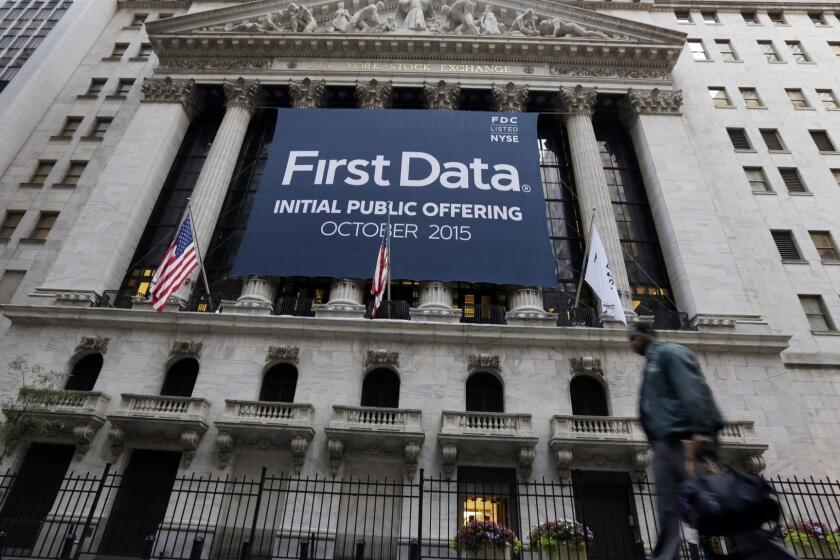 FILE - In this Oct. 15, 2015 file photo, a banner for First Data Corp. adorns the facade of the New York Stock Exchange, to mark the company's IPO. Fiserv is buying First Data in a $22 billion all-stock deal, creating a giant player in the payments and financial technology sector. First Data shareholders will receive about .30 shares of Fiserv for every share of First Data they own, according to the deal announced Wednesday, Jan. 16, 2019 a premium of about 29 percent. (AP Photo/Richard Drew, File)