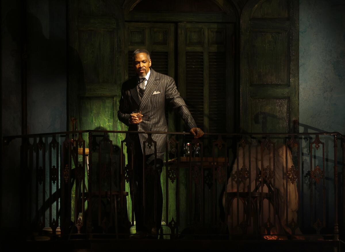 A man in a dapper pinstriped suit and standing on a balcony.