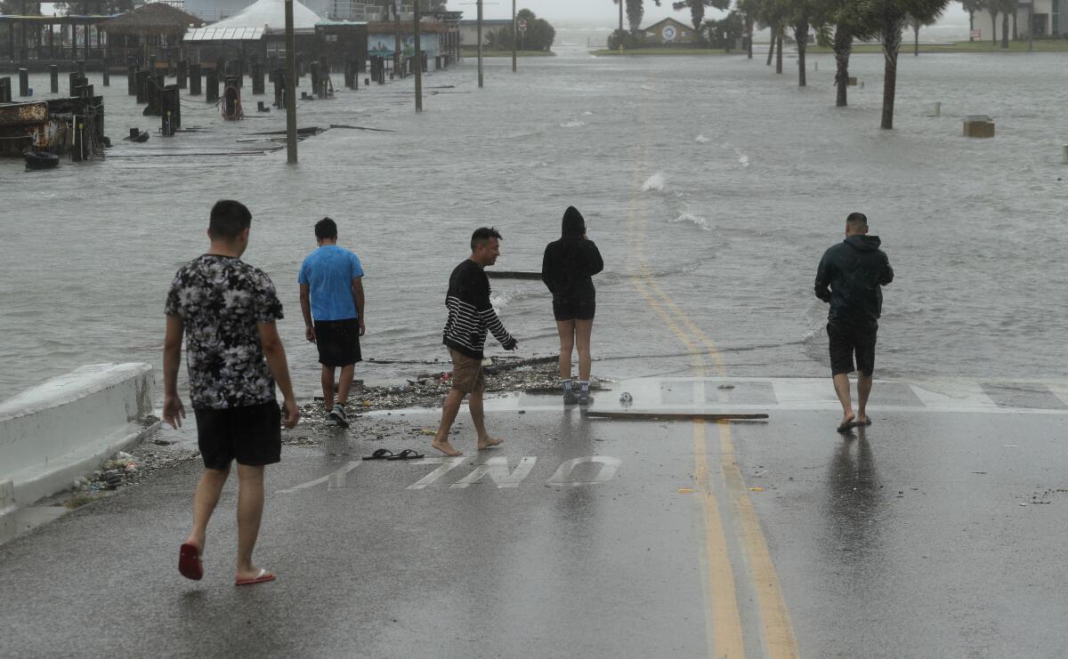 Onlookers watch floodwaters begin to cover a road as Hurricane Hanna makes landfall Saturday in in Corpus Christi, Texas.