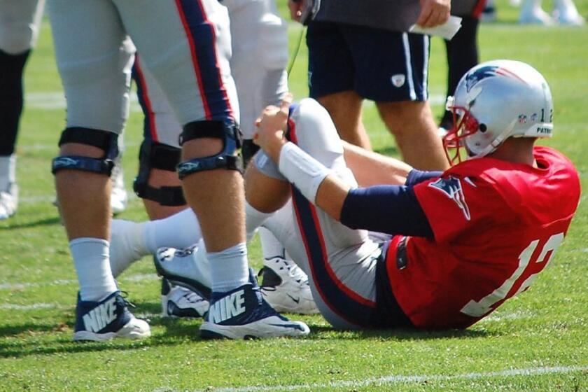 Tom Brady holds his knee after an injury.