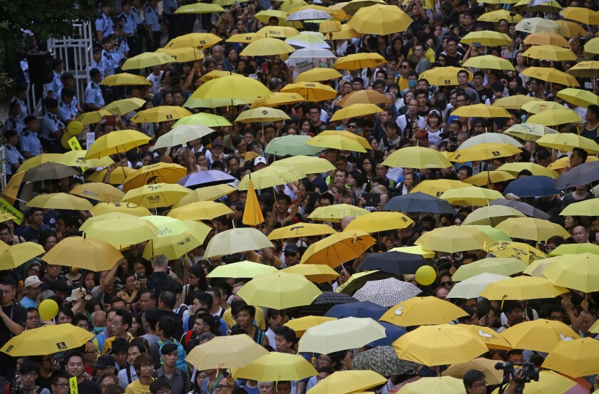 Protesters holding yellow umbrellas gather to observe a moment of silence Monday outside the government headquarters in Hong Kong to mark the first anniversary of the "Umbrella Movement."