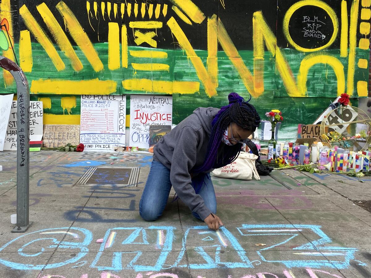 Tori Willis, 15, chalks CHAZ, short for Capitol Hill Autonomous Zone, on a sidewalk.