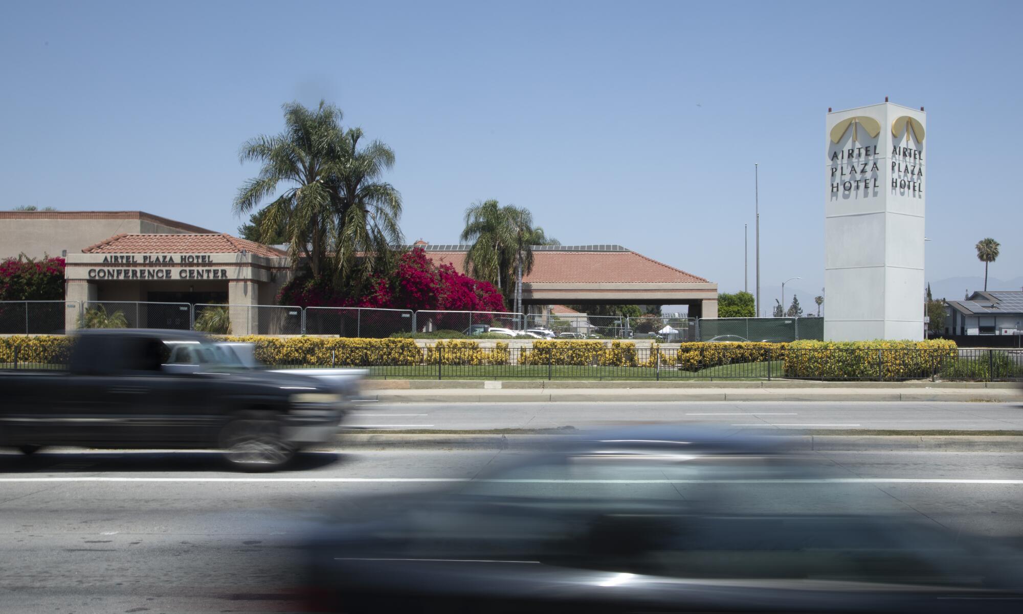 A car drives by on the street in front of a hotel complex