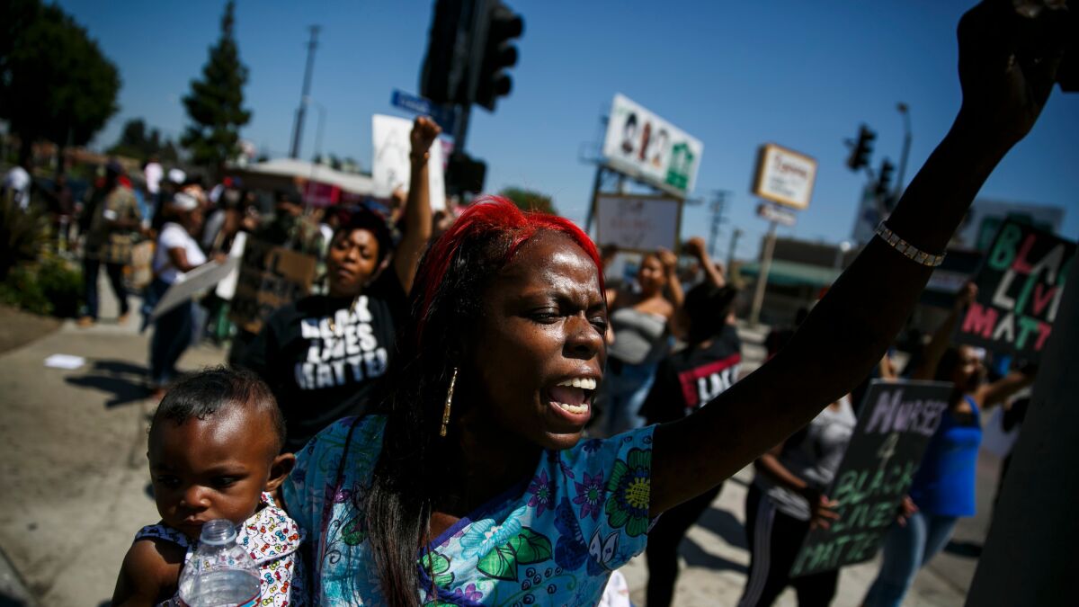 Ernestine Brass, holding her daughter, protests the recent deaths of Alton Sterling and Philando Castile in Los Angeles, Calif., on July 7, 2016.