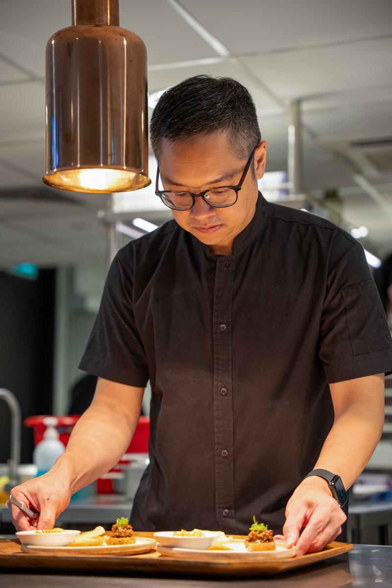 Şef Malcolm Lee, Singapur'daki Pangium restoranında mutfakta bir yemek hazırlıyor.
