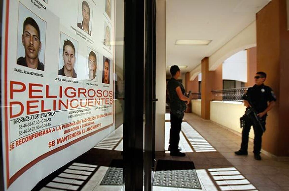 Police guard the office of Mayor Hugo Torres at Rosarito Beach City Hall, where a wanted poster shows 13 suspects it labels "dangerous criminals" who are former Tijuana police officers charged with kidnapping.