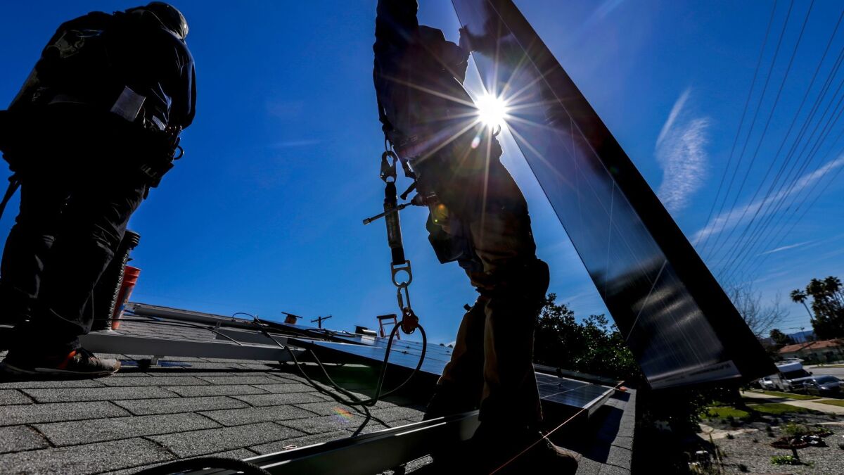 Contractors install a solar energy system at a home in Van Nuys.