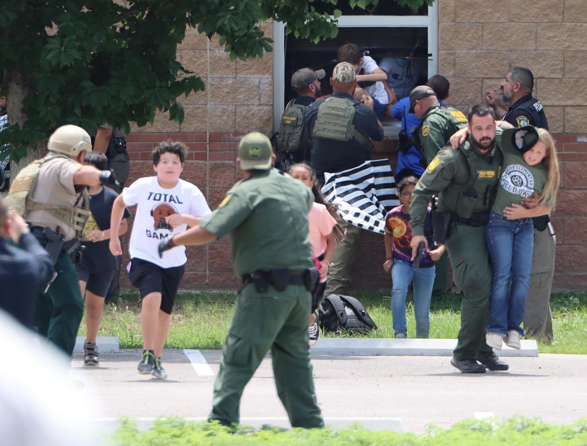 Children are helped out of windows at Robb Elementary during the school shooting on Tuesday, April 24, 2022.
