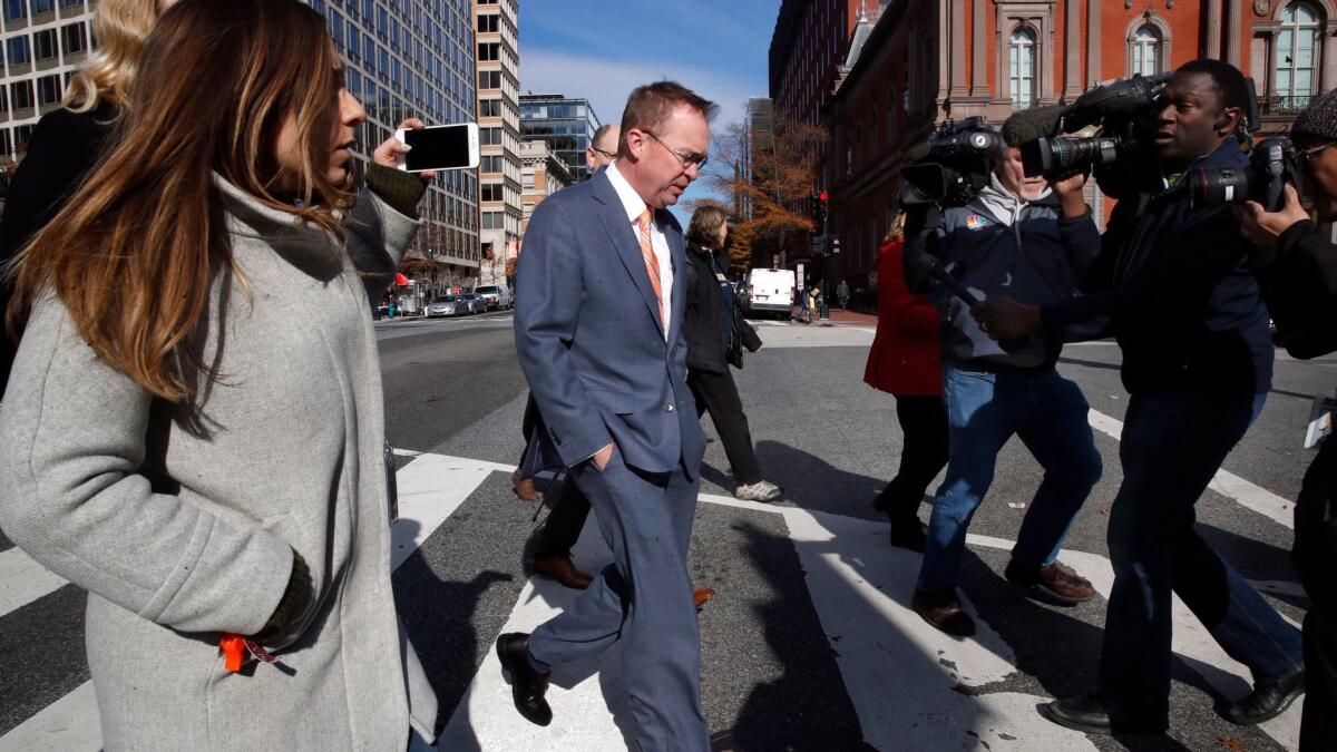 Mick Mulvaney, center, walks from the Consumer Financial Protection Bureau headquarters in Washington to the White House on Monday.