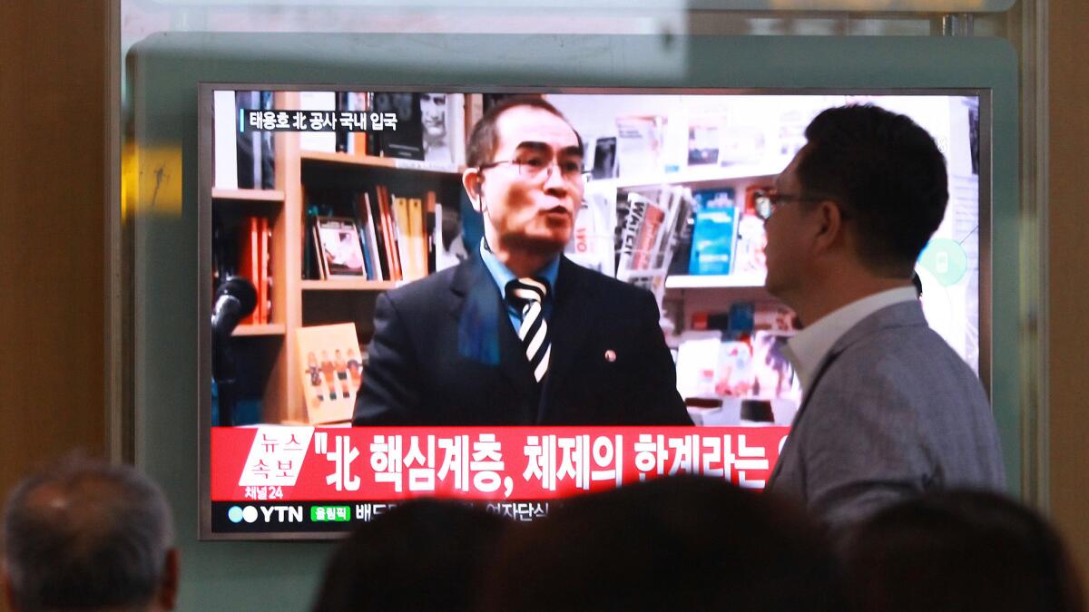 South Koreans at a Seoul railway station watch a TV news program showing a file image of Thae Yong Ho.