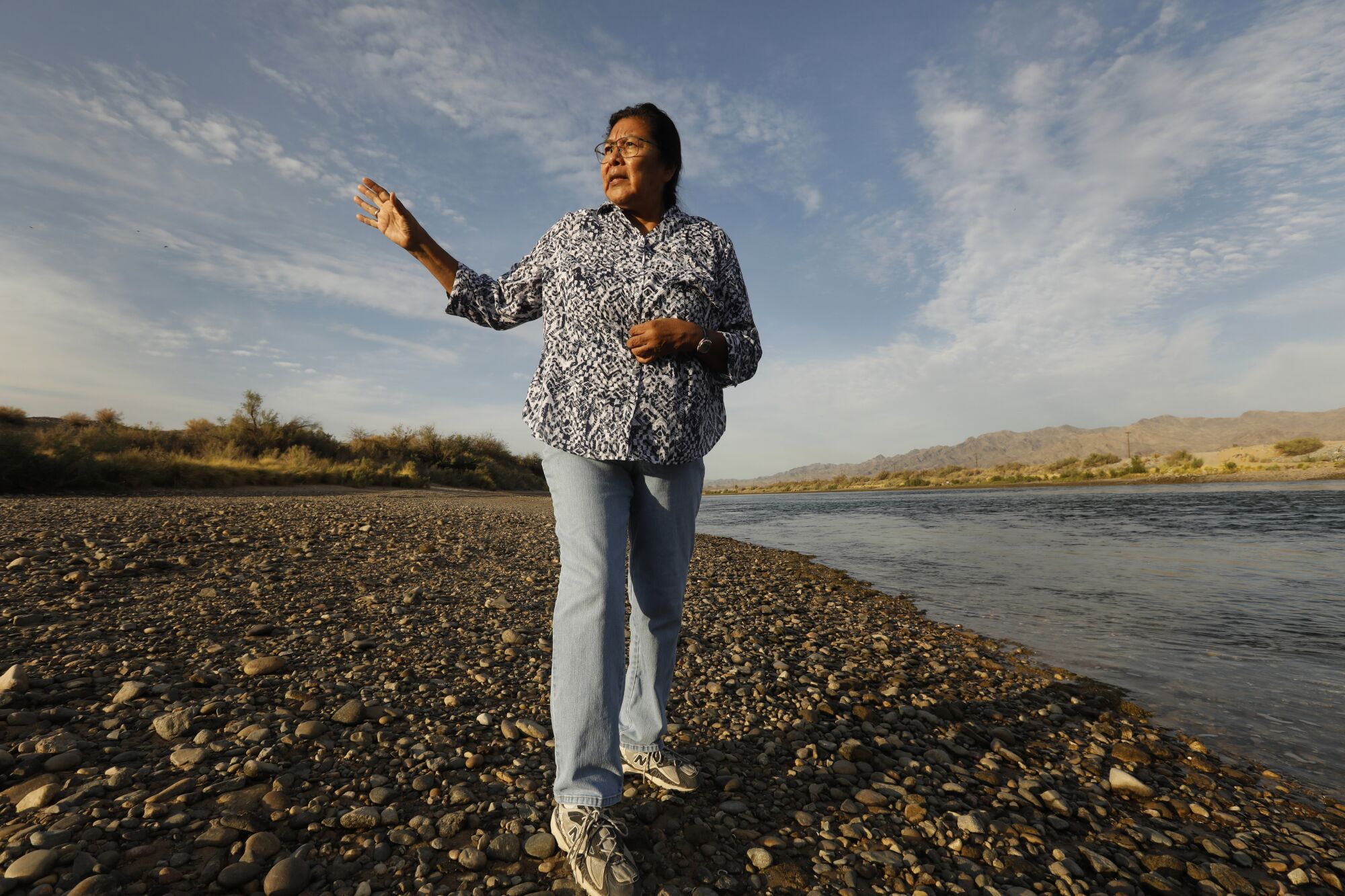 Une femme fait des gestes en parlant et en marchant le long d'une rivière