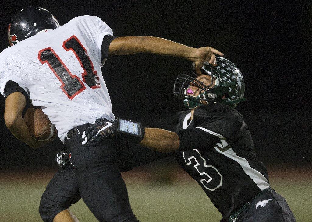 Costa Mesa High's Cameron Curet, right, holds on for a tackle on Katella's Damian Durango during the first half in a nonleague game at Jim Scott Stadium on Thursday. Durango was penalized for an illegal use of hands.