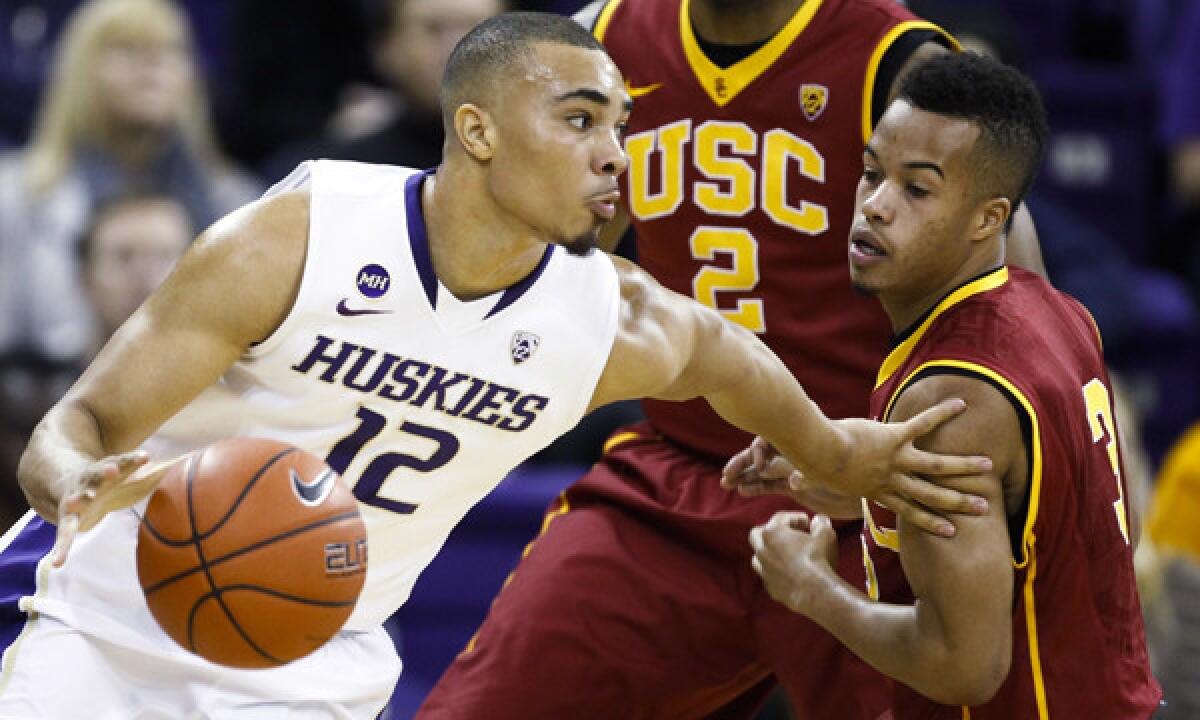 Washington guard Andrew Andrews, left, dribbles past USC guard Chass Bryan during the first half of the Trojans' 82-75 road loss Saturday.