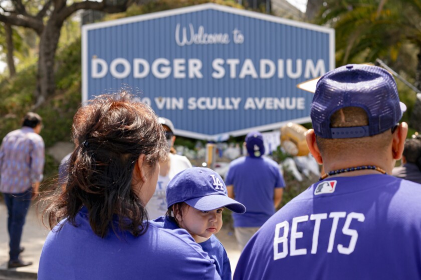 Suzanna Jimenez holds her daughter while looking at the memorial for Vin Scully