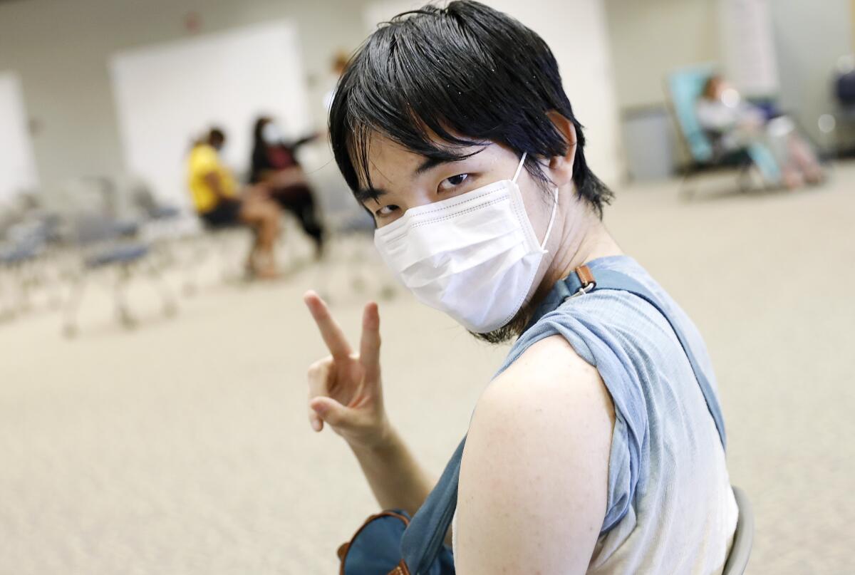 A college student flashes a peace sign before receiving Pfizer vaccination