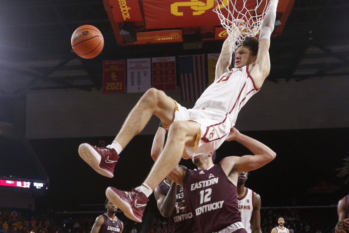 Southern California guard Drew Peterson (13) dunks over Eastern Kentucky forward Michael Wardy (12) during the second half of an NCAA college basketball game Tuesday, Dec. 7, 2021, in Los Angeles. USC won 80-68. (AP Photo/Ringo H.W. Chiu)