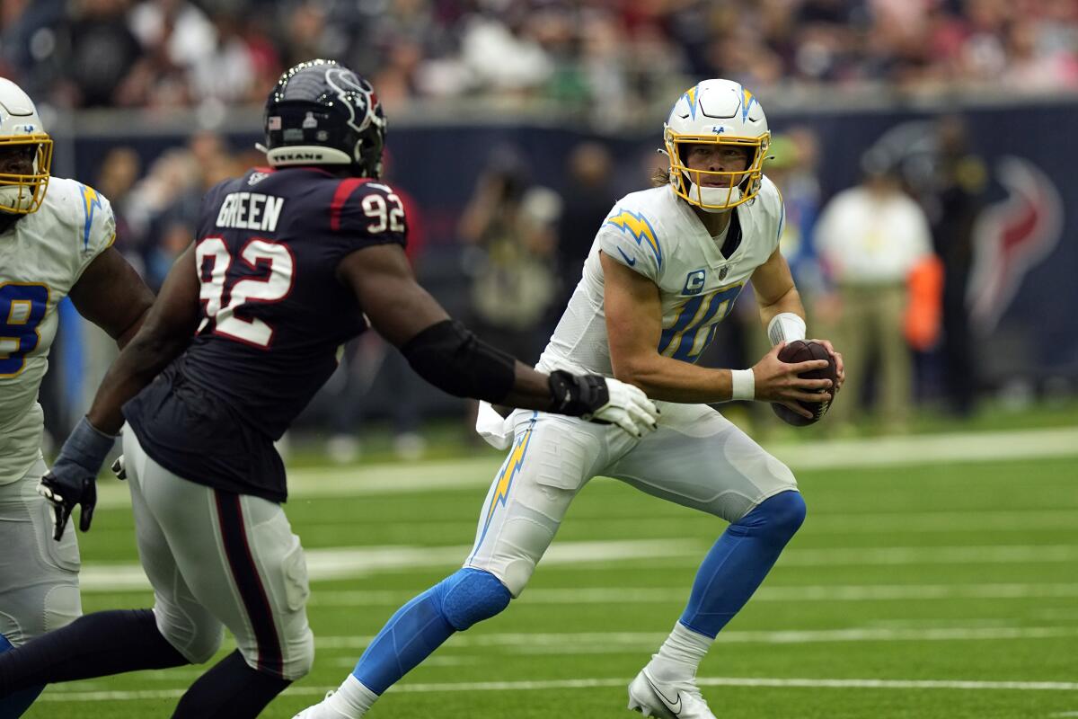 Chargers quarterback Justin Herbert is pursued by the Texans' Rasheem Green.