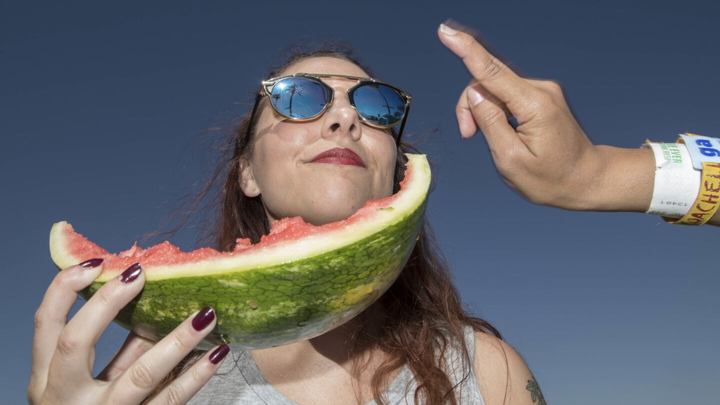 INDIO, CALIF. -- SATURDAY, APRIL 15, 2017: Shari Chaffin, 23, of Madera enjoys a slice of watermelon at the Coachella Music and Arts Festival in Indio, Calif., on April 15, 2017. (Brian van der Brug / Los Angeles Times)